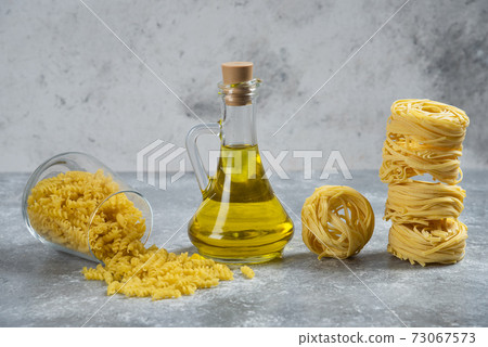 Raw nest pasta with a glass bottle of oil 73067573