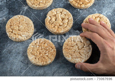 Male hands holding crispbread on marble background Male hands holding crispbread on marble background 73067696