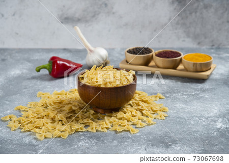 A wooden bowl full of raw macaroni and spices A wooden bowl full of raw macaroni and spices 73067698