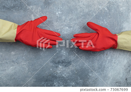 Hands in red protective gloves on marble background Hands in red protective gloves on marble background 73067699