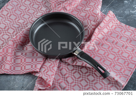 An empty black frying pan on a tablecloth An empty black frying pan on a tablecloth 73067701