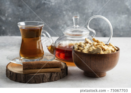 A glass cup of tea with wooden bowl full of crackers A glass cup of tea with wooden bowl full of crackers 73067703