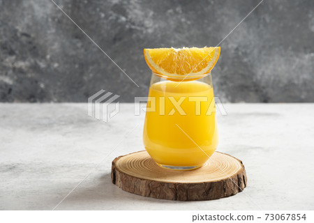 A glass cup of fresh orange juice on a wooden board A glass cup of fresh orange juice on a wooden board 73067854