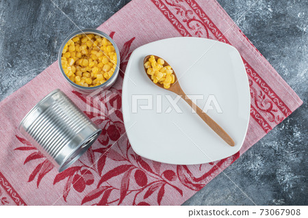 A wooden spoon of popcorn seeds on an empty plate A wooden spoon of popcorn seeds on an empty plate 73067908