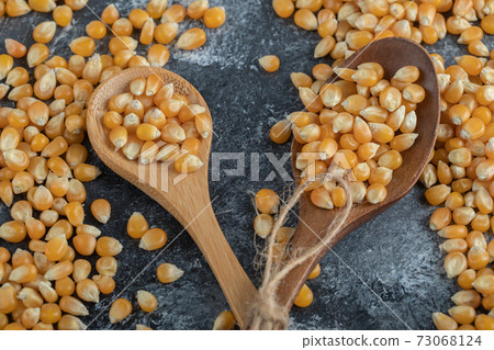 Wooden spoons of sweet corns on marble background 73068124