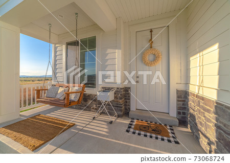 Front porch of modern home with swinging chair Front porch of modern home with swinging chair 73068724