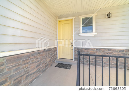 Front porch of suburban home with a yellow door 73068805