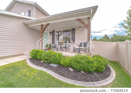 Neatly landscaped small garden in front of porch 73068814
