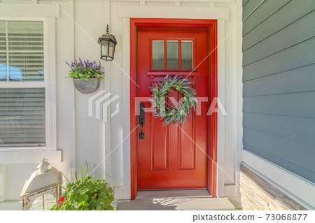 Red front door of modern home with green wreath Red front door of modern home with green wreath 73068877