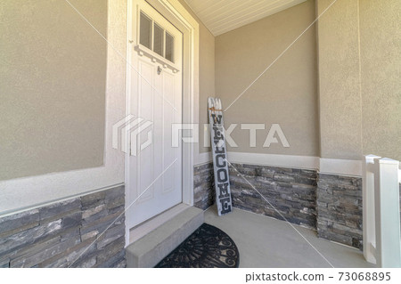Front door and porch of home with welcome sign 73068895