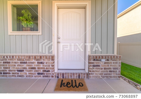 Front door and porch of home with hello mat 73068897
