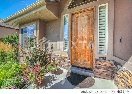 Front porch of house with wooden door and garden 73068959