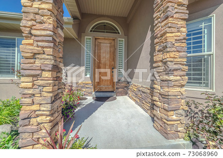 Front porch and door of house with stone pillars 73068960