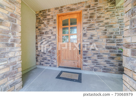 Wooden front door of modern house with stone walls Wooden front door of modern house with stone walls 73068979