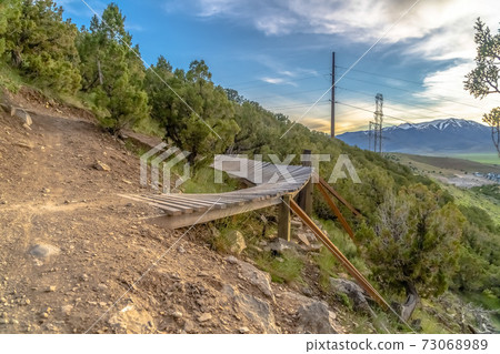 Wooden struts supporting an elevated boardwalk with bushes 73068989