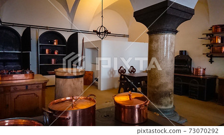 Kitchen of the old castle. Copper pans, baking molds and other kitchen utensils Kitchen of the old castle. Copper pans, baking molds and other kitchen utensils 73070292