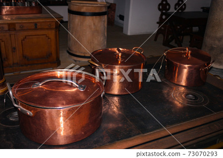 Kitchen of the old castle. Copper pans, baking molds and other kitchen utensils Kitchen of the old castle. Copper pans, baking molds and other kitchen utensils 73070293