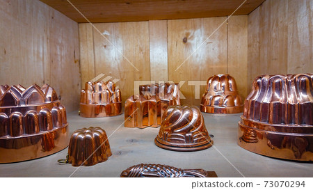 Kitchen of the old castle. Copper pans, baking molds and other kitchen utensils 73070294