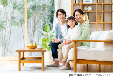 一個在客廳裡放鬆的年輕家庭 73072476