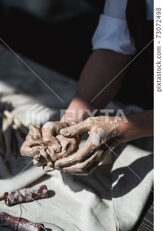Woman's hands wet and dirty after working with clay in a pottery studio Woman's hands wet and dirty after working with clay in a pottery studio 73072498