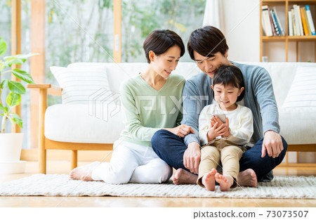 A young family looking at a smartphone in the living room 73073507