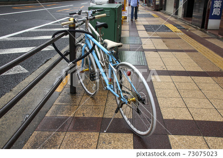 Bicycle parked on a wet sidewalk Bicycle parked on a wet sidewalk 73075023