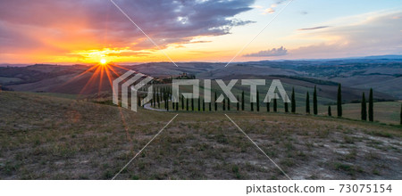 Tuscany, cypress trees road., Crete Senesi rural sunset landscape. Countryside farm, cypresses trees, green field, sun light and cloud. Italy, Europe. Tuscany, cypress trees road., Crete Senesi rural sunset landscape. Countryside farm, cypresses trees, green field, sun light and cloud. Italy, Europe. 73075154