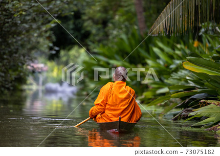 Buddhist monk in small wooden boat sailing in canal for receive food in morning, The culture tradition Buddhist monk of making merit to monks morning, Popular tourist attraction on canals of Thailand. Buddhist monk in small wooden boat sailing in canal for receive food in morning, The culture tradition Buddhist monk of making merit to monks morning, Popular tourist attraction on canals of Thailand. 73075182