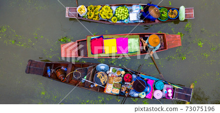 Aerial view famous floating market in Thailand, Damnoen Saduak floating market, Farmer go to sell organic products, fruits, vegetables and Thai cuisine, Tourists visiting by boat, Ratchaburi, Thailand 73075196