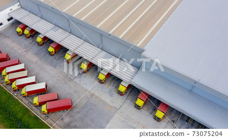 Aerial view logistics center in industrial city, Industrial warehouse loading dock where many truck with semi trailers load merchandise, Trucks loading at logistic center goods warehouse. 73075204