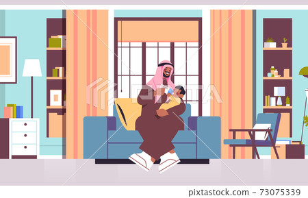 arab father feeding little son with milk bottle fatherhood parenting concept dad spending time with baby arab father feeding little son with milk bottle fatherhood parenting concept dad spending time with baby 73075339