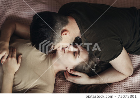 Happy couple lying in bed together and kissing at home 73075801
