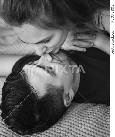 Happy couple lying in bed together and kissing at home 73075802