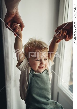 Fathers hands pull happy son up by hands at home. Top wiev 73075803