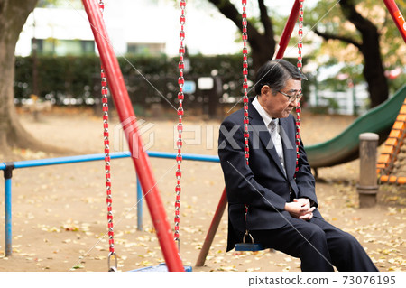 A businessman twilight on a swing in the park A businessman twilight on a swing in the park 73076195