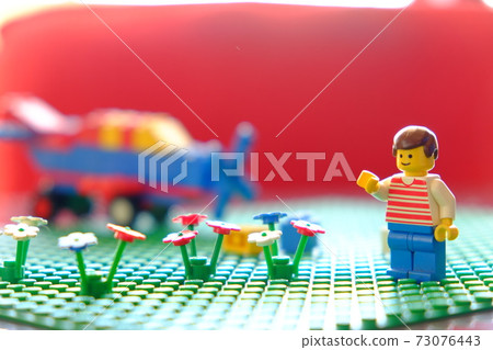 Illustration of a boy, a flower and a helicopter on a lego lawn Illustration of a boy, a flower and a helicopter on a lego lawn 73076443
