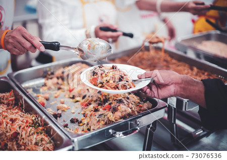 Homeless and needy people receive help, receive food from volunteers 73076536