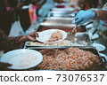 Homeless and needy people receive help, receive food from volunteers 73076537