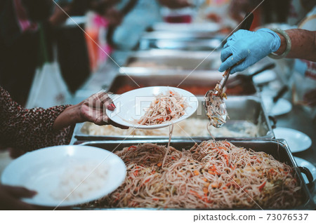 Homeless and needy people receive help, receive food from volunteers 73076537