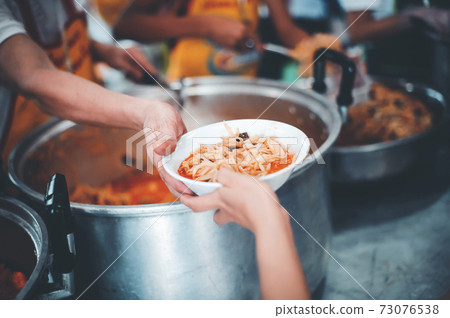 Homeless and needy people receive help, receive food from volunteers 73076538