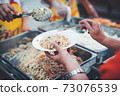 Homeless and needy people receive help, receive food from volunteers 73076539