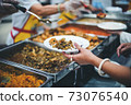Homeless and needy people receive help, receive food from volunteers 73076540