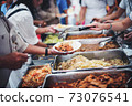 Homeless and needy people receive help, receive food from volunteers 73076541
