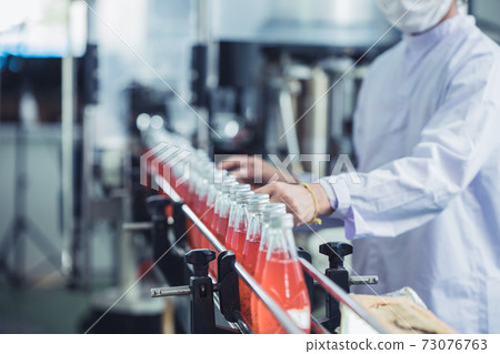 Drink factory - closeup hygiene worker working check juice glass bottled in production line 73076763