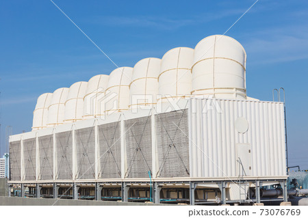 Air cooling tower for HVAC chilling units at building rooftop outdoor blue sky. Air cooling tower for HVAC chilling units at building rooftop outdoor blue sky. 73076769