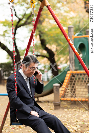 Businessman making a phone call Park swing 73077383
