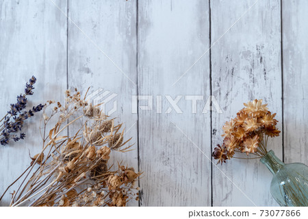 Fashionable dried flowers on a white board wall 73077866