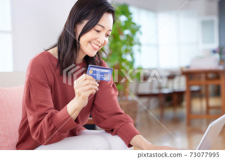 中年女人在客廳裡享受在線購物 73077995