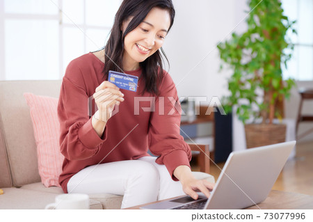 中年女人在客廳裡享受在線購物 73077996