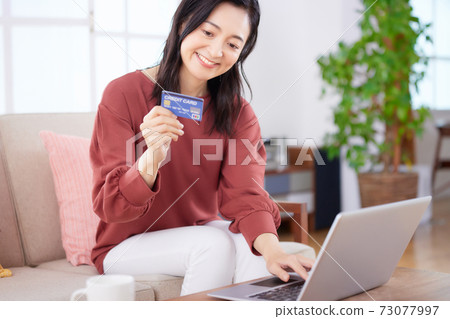 Middle-aged woman enjoying online shopping in the living room 73077997